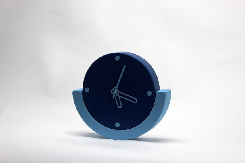 a photograph of an analogue clock in tones of blue against a white backdrop