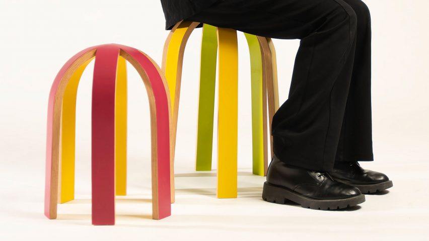 a photograph of a person sat on a stool in an arched shape and in tones of yellow, green and red