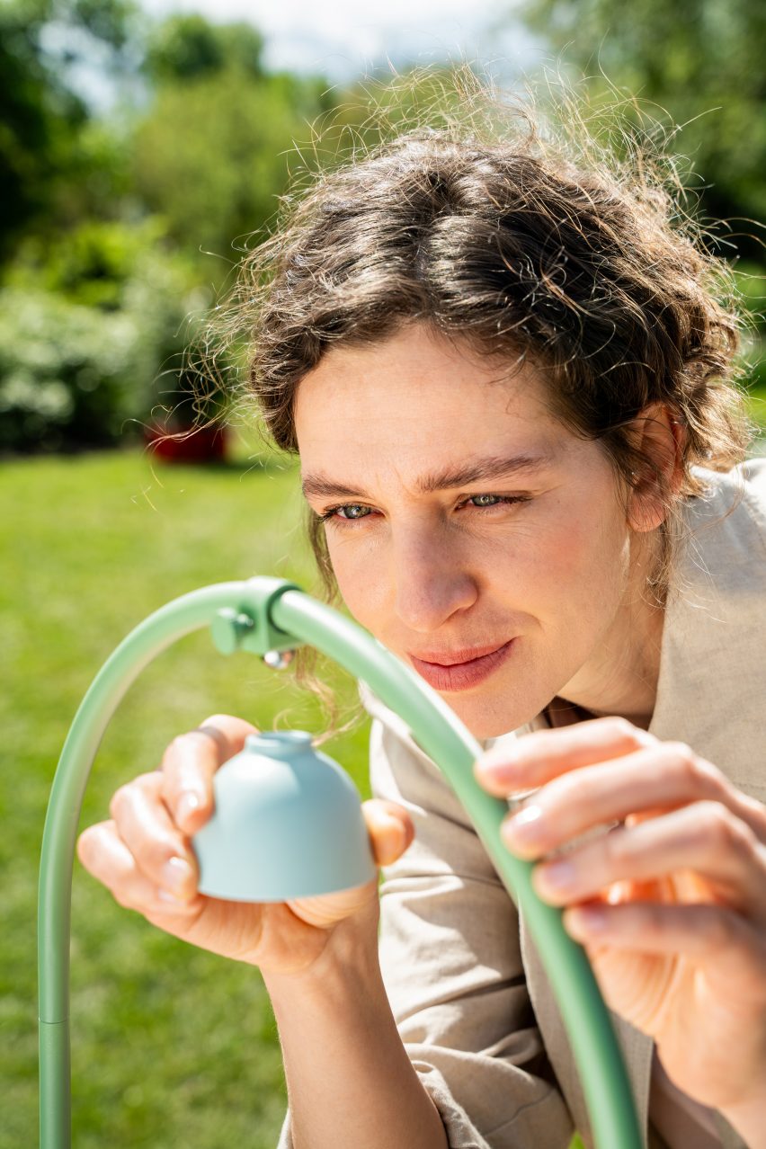 Photo of a woman attached a small pastel blue domed module to the Wonder Blocks trellis out in a sunny garden