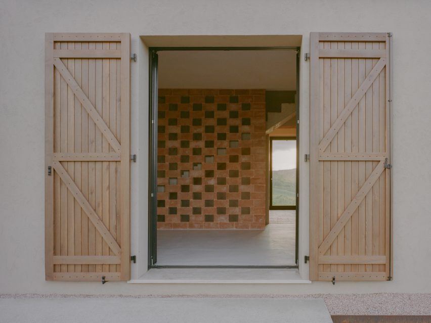 View through shuttered doors into a room with a lattice brickwork wall