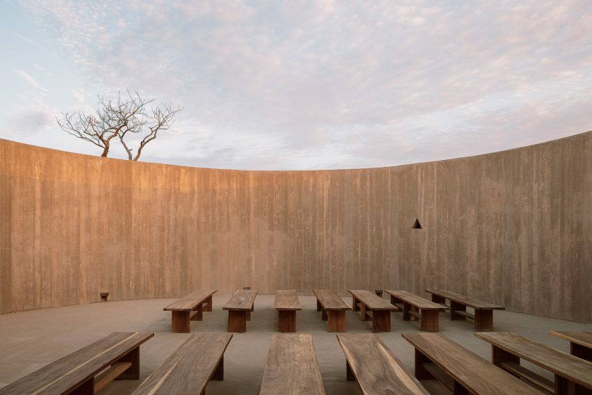 Curved concrete wall with a small triangular aperture as its only break