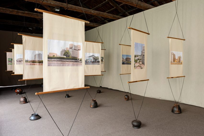 Photo of a the Togo exhibition at the Venice Architecture Biennale showing building photography presented on textile banners suspended in space and weighted by ceramic pots at the bottom