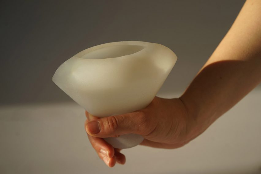 Photo of a silicone vessel with a person's hand holding onto a handle at the bottom