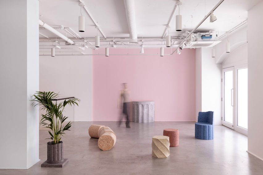 Photograph of an open-plan gallery exhibition showing various pieces of colourful granite-looking furniture such as stools, tables and benches. 