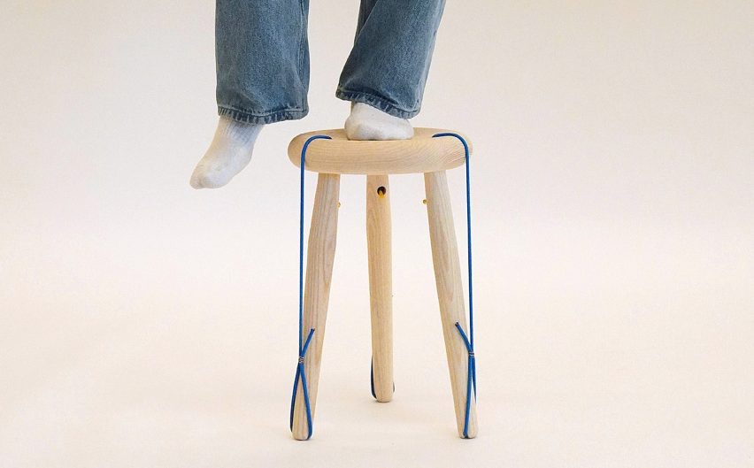 Photo of legs, with one standing on a light wood stool with blue cord