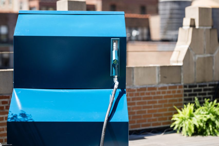 Photo of a side view of the Aircela air-to-fuel machine showing bright blue side panels and a petrol station-style hand pump