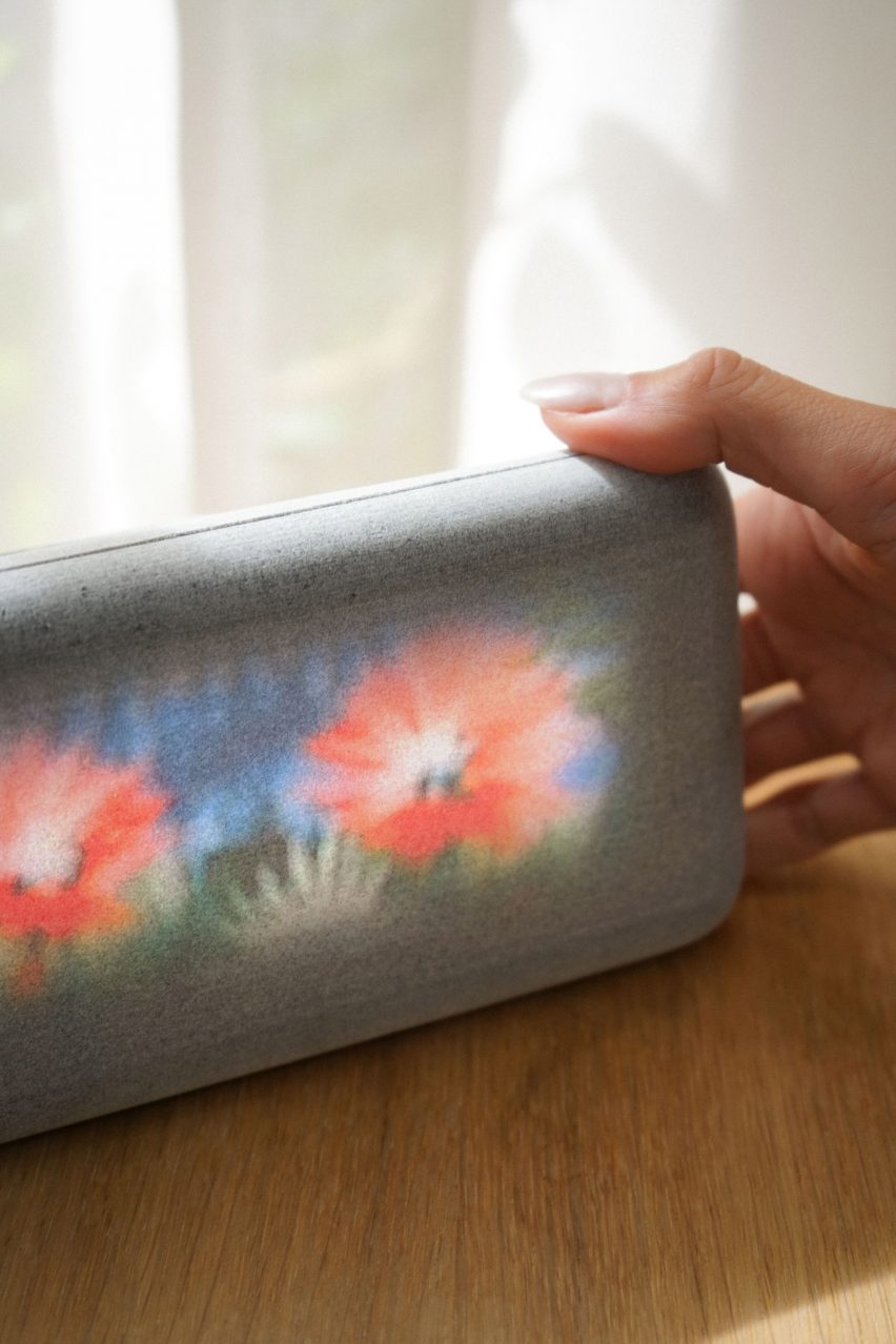 Close-up on the Dream Recorder, showing a grainy video of bright red flowers playing on a slim rectangular white device