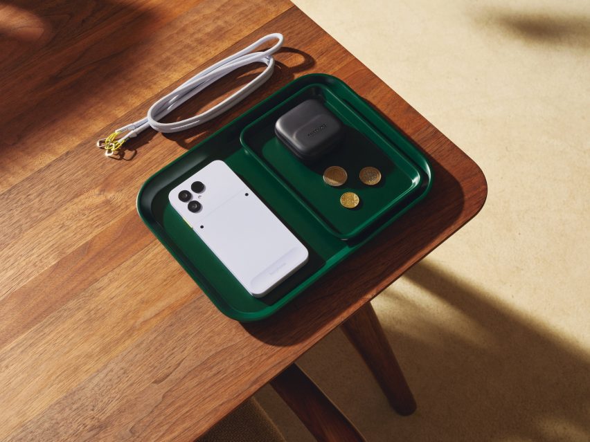 Photo of a white Fairphone 6 placed neatly in a tray on a table with a lanyard sitting near it