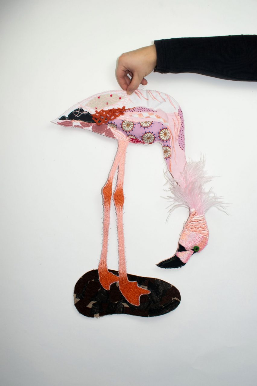 a photograph of a person holding a model of a flamingo in tones of pink, red and blue