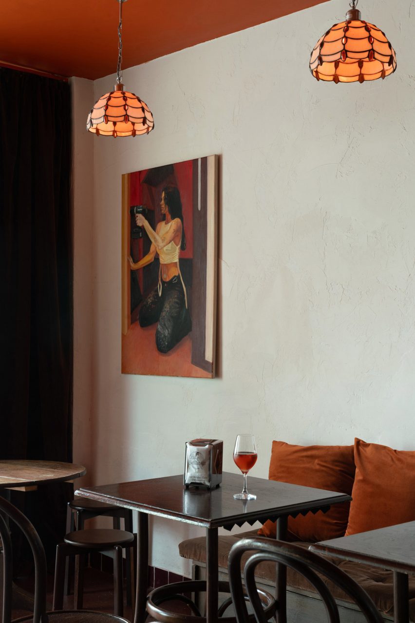Bar interior with wooden seating, glass pendant light shades and painting on the wall