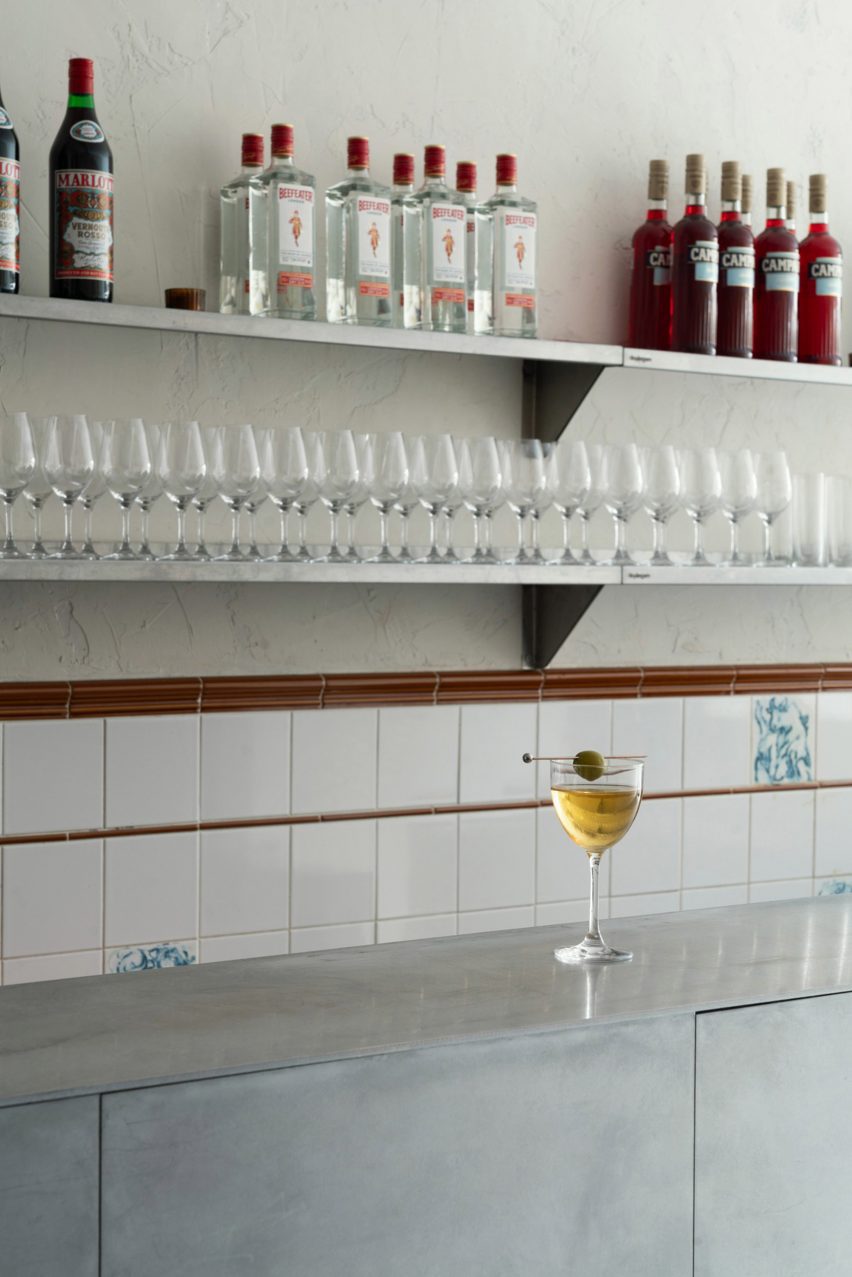 Bar interior with aluminium bar and metal shelving behind holding bottles and glasses
