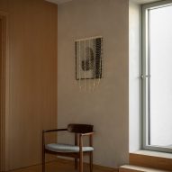 Wooden chair below contemporary artwork in hotel room