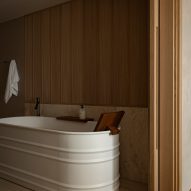 Deep white bathtub and wood-panelled walls