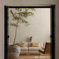 Lounge area with long white sofa and large ceramic pot