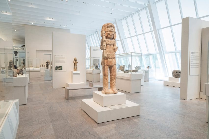 Stone works from the ancient Americas beside large slanted windows