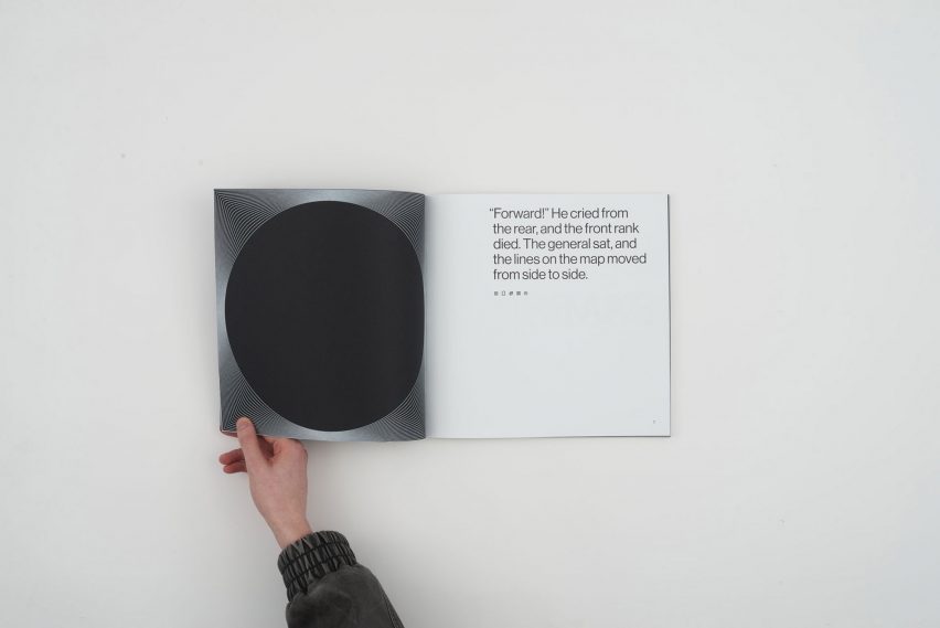 a photograph of a person's hand holding open a book in tones of silver, black and white