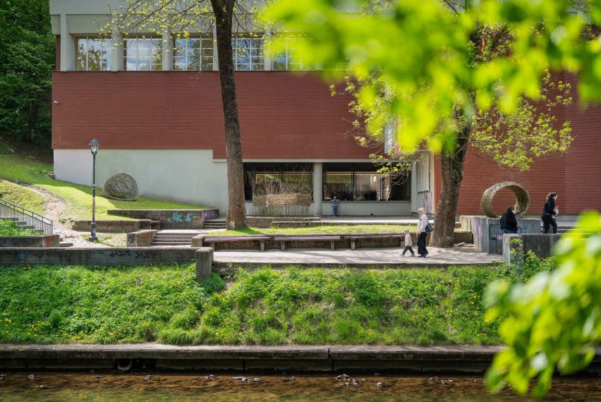 a photograph of a campus in tones of white and brown with green trees surrounding it