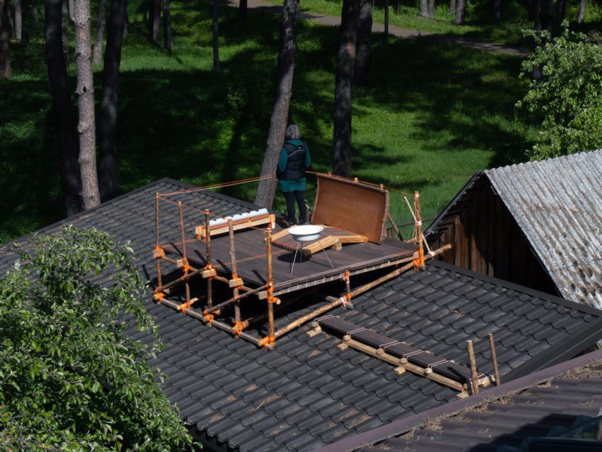 a photograph of a wooden structure on a roof, with a person standing on it