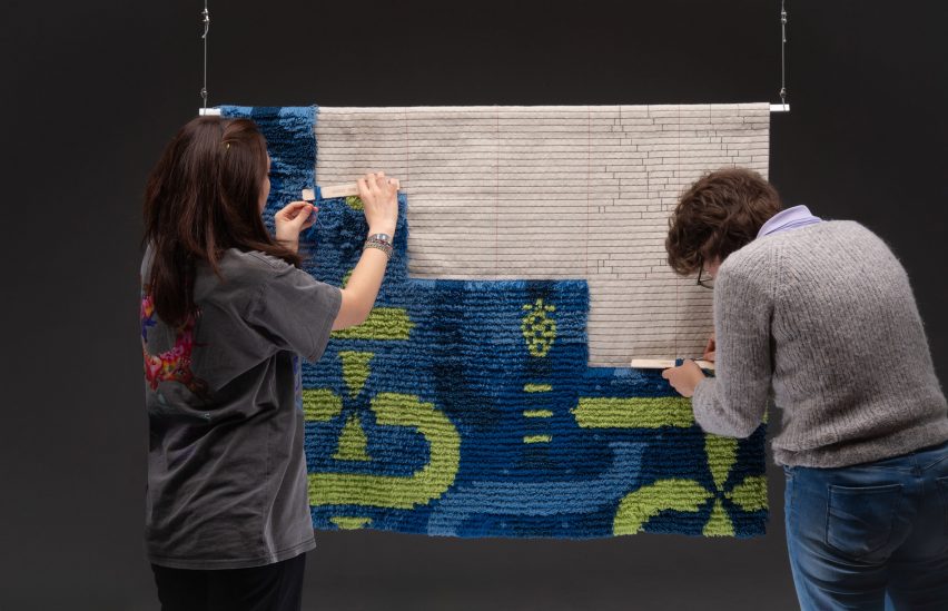 a photograph of people tending to a tapestry in tones of blue, green and beige