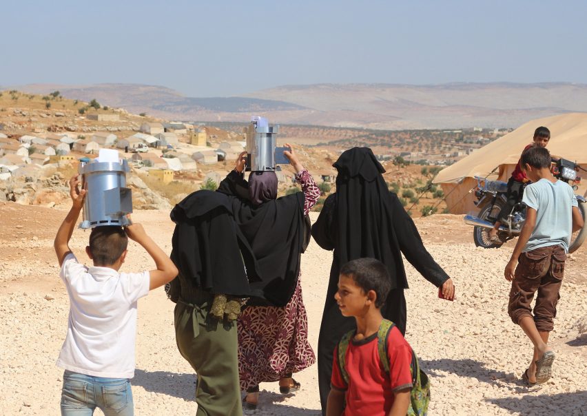 People carrying Fire for Life cooking stoves by Escea in a Syrian refugee camp