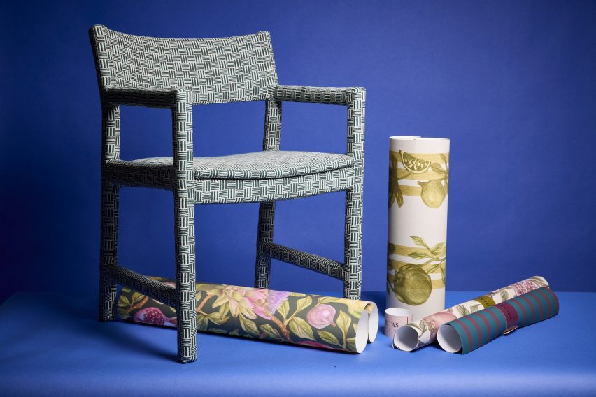 a photograph of a chair and rolls of fabrics against a blue backdrop
