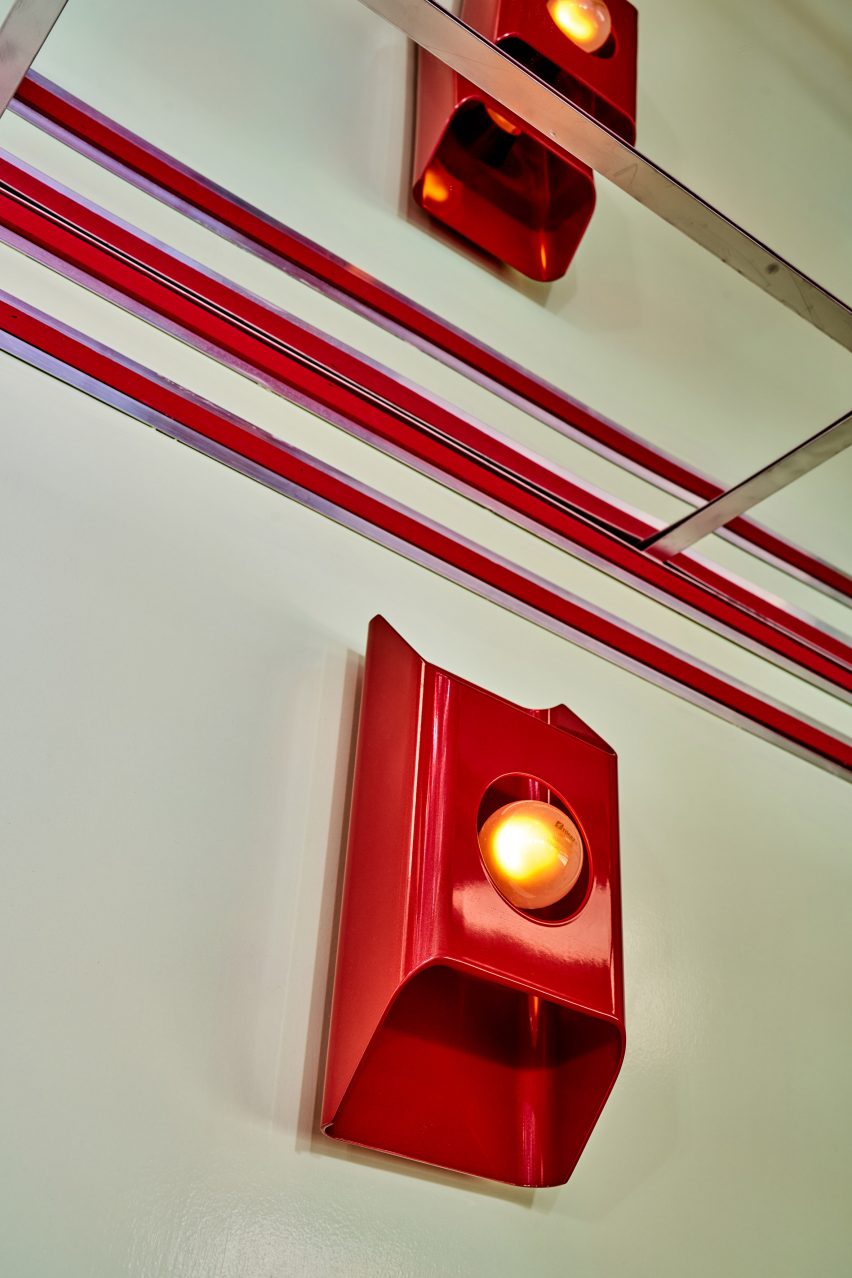 Glossy red sconce reflected in a mirrored ceiling