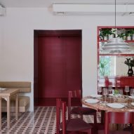 Red wall panels, drinks cabinet and chairs inside wine bar