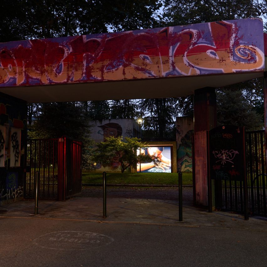 a photograph of a park entrance at night with graffiti in tones of pink and orange