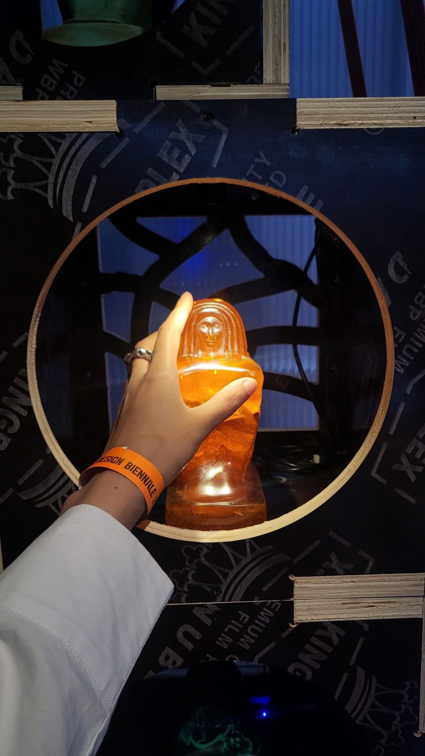 a photograph of an orange figure model with a person's hand holding it
