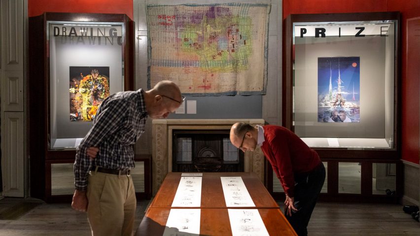 a photograph of two people looking at drawings on a table