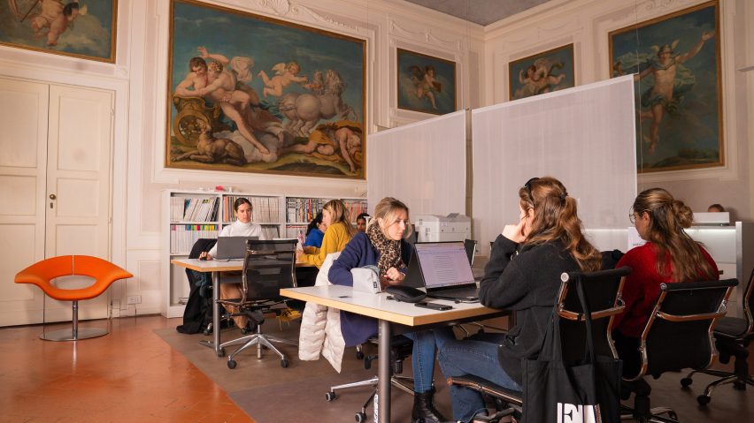 Students on laptops in a classical-style room
