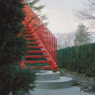 Red steel staircase resting on stones