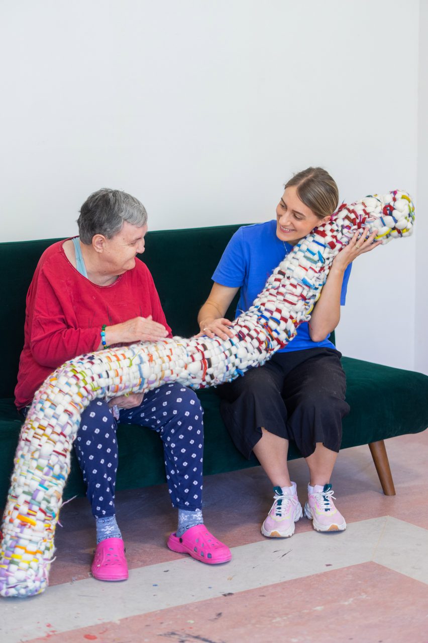 a photograph of two people sat on a green sofa with a large soft toy
