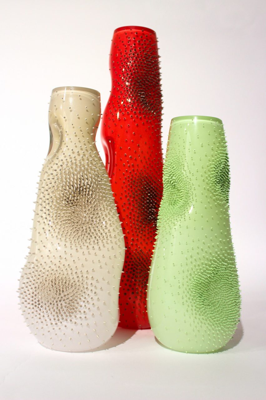a photograph of abstract-shaped and textured vases in tones of red, beige and green