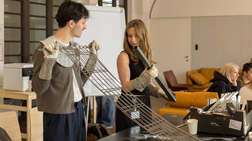 Two people in a workshop working on a metal structure