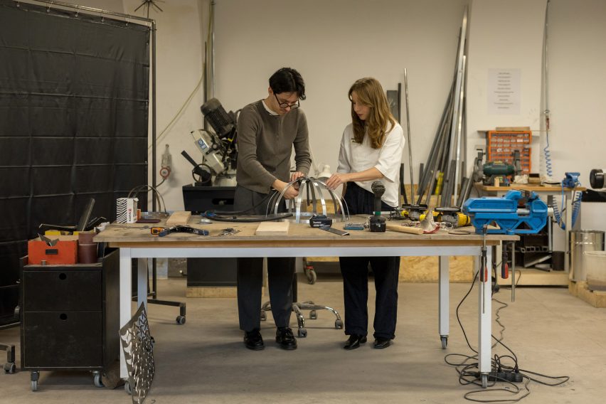 Two people in a workshop working on a metal structure