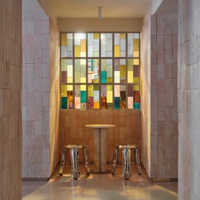 Photo of stools and a table by a stain glass window