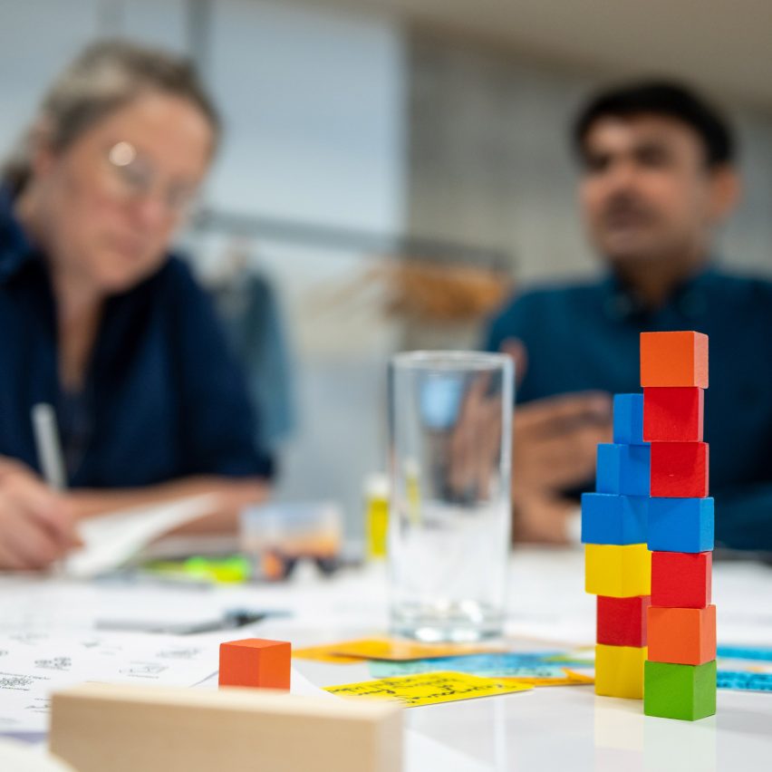 a photograph of coloured building blocks on a table with people in the background