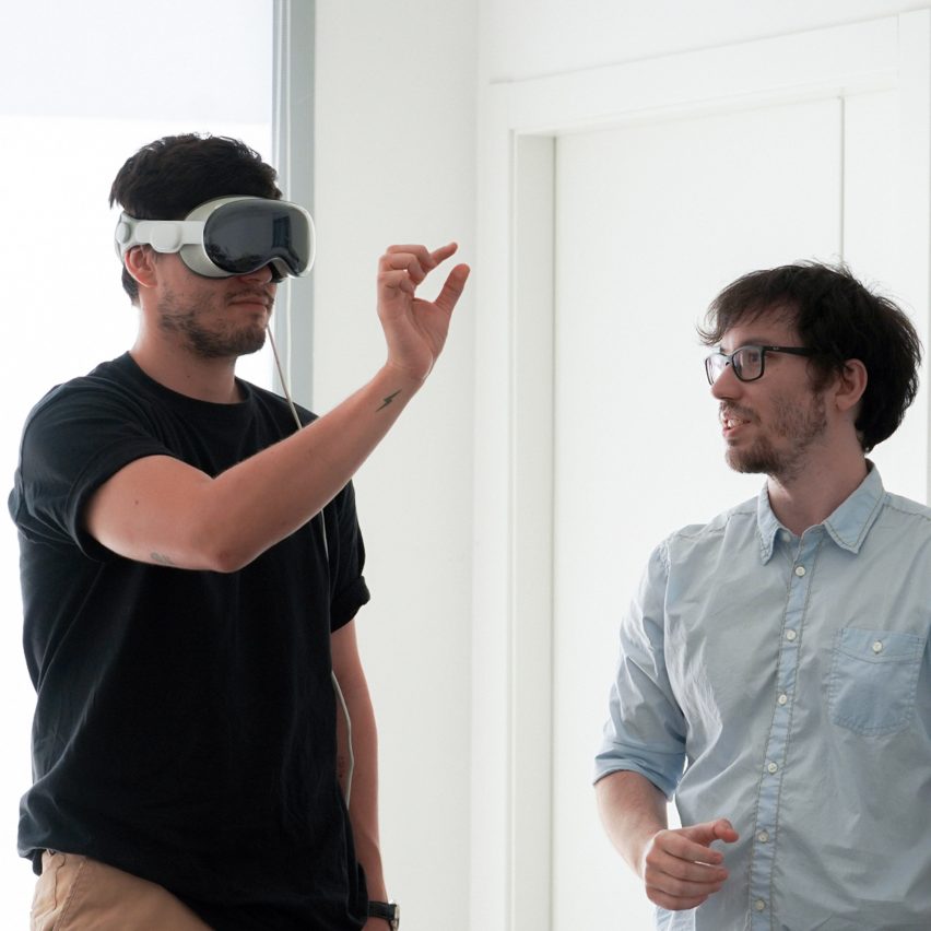 a photograph of two people, one with a VR headset on