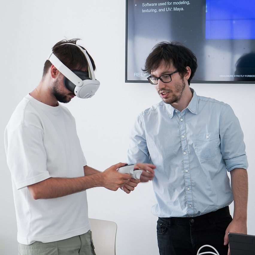 a photograph of two people, one with a VR headset on