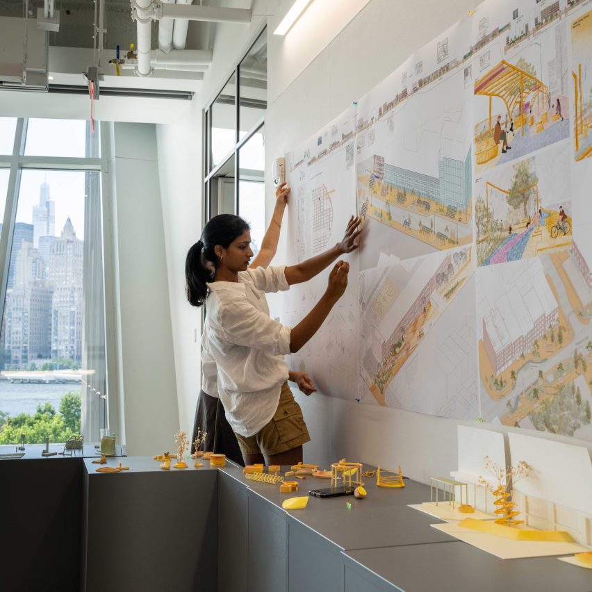 a photograph of a student placing work on wall