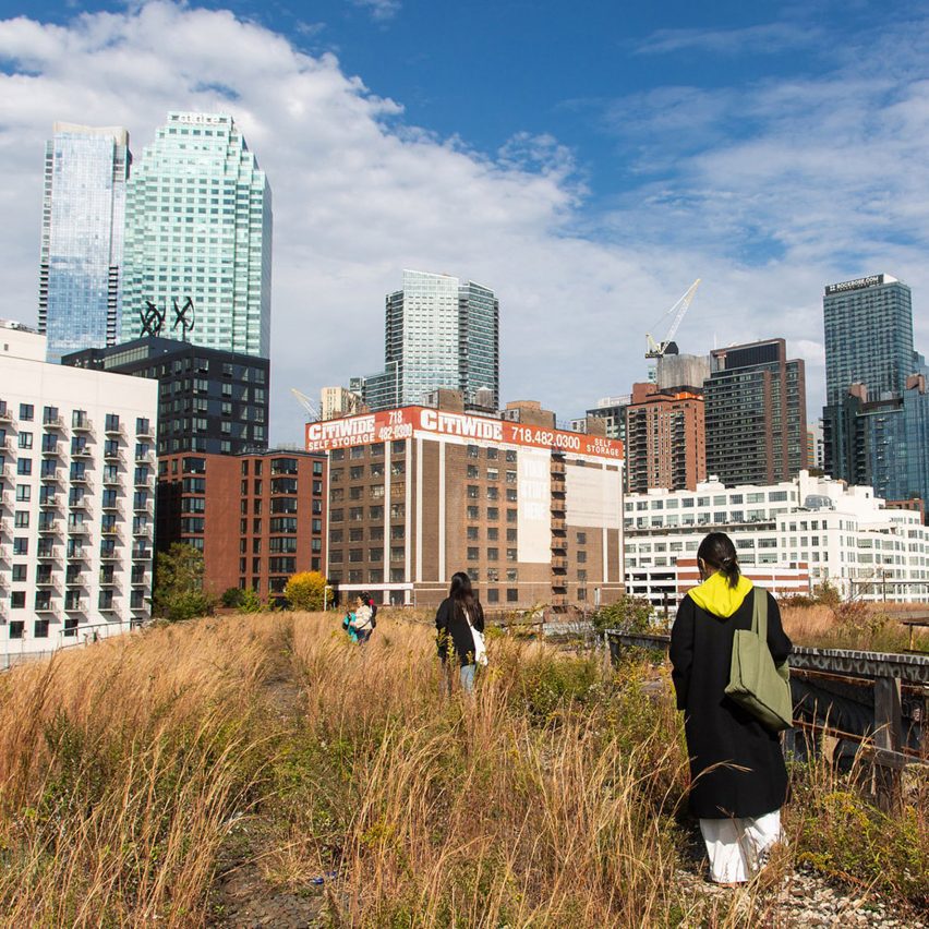 a photograph of people walking through a field with high rise buildings surrounding it