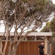 Person with dog outside single-storey house Australia