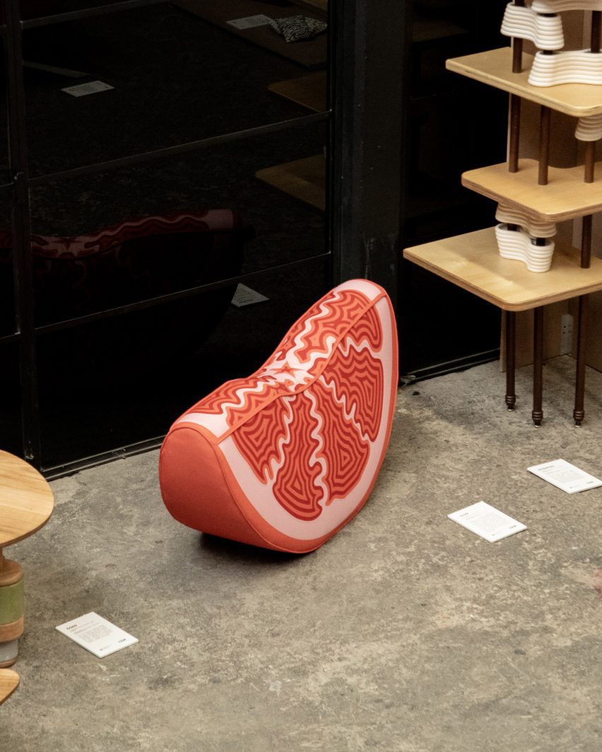 a cushion in the form of a citrus fruit segment, in tones of pink and red