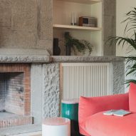 Living room with pink sofa and stone fireplace in revamp of 1960s villa by StudioTamat