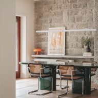 Dining room with stone wall in revamp of 1960s villa by StudioTamat