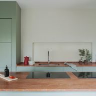 Mint-green kitchen with red travertine island in revamp of 1960s villa by StudioTamat