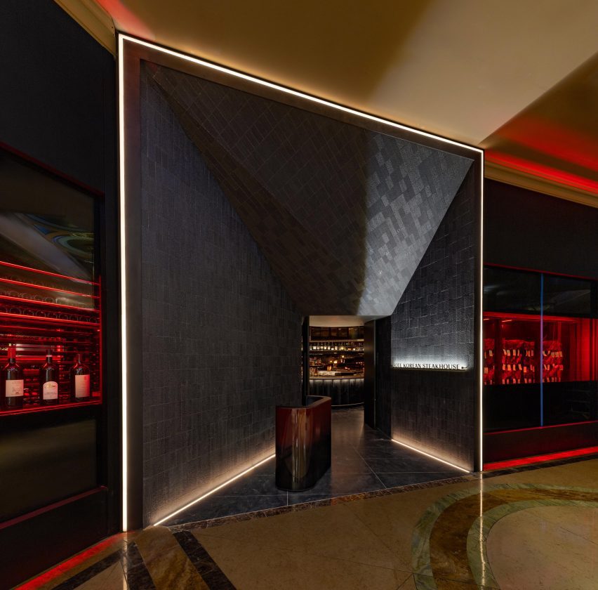 Entrance to a restaurant: an angular tunnel lined with dark stone tiles