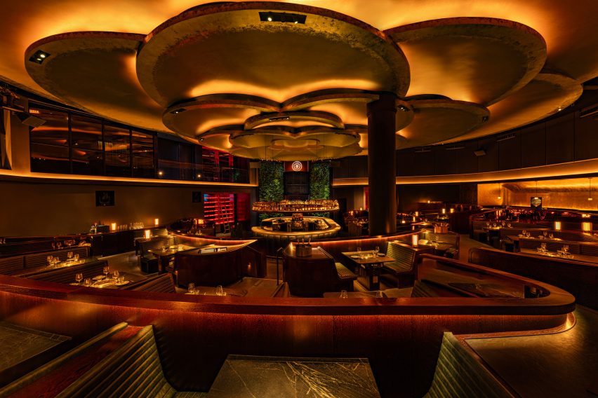 Tables facing a pair of green walls flank an elevated DJ booth