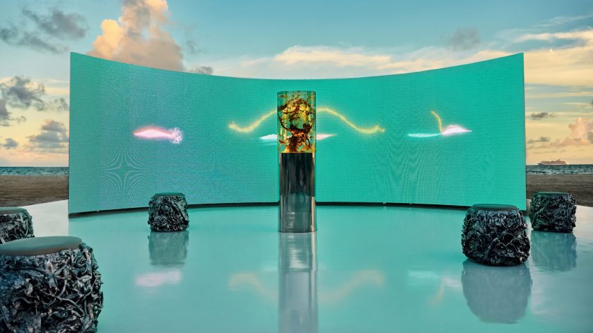 Daytime view of the Plant Pulses installation with a curved turquoise LED screen framing the resin sculpture on Miami Beach